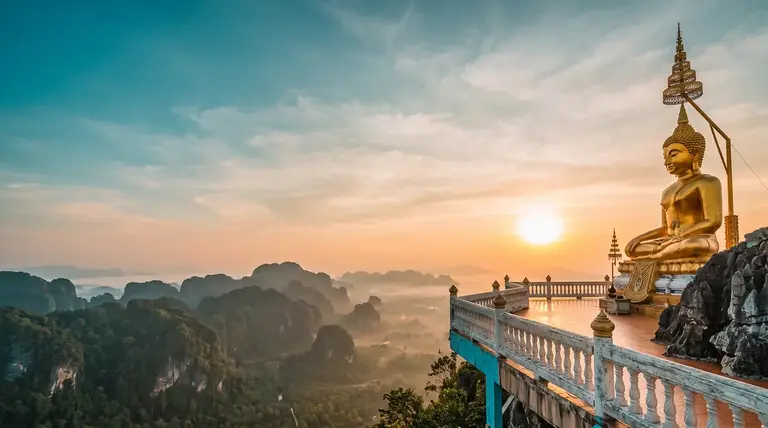 Sunrise over the golden Buddha at the Tiger Cave Temple summit in Krabi, Thailand